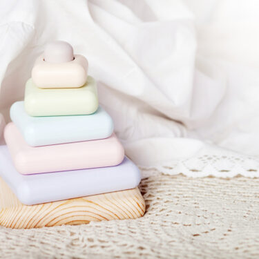 Pastel wooden stocking blocks sitting on lace cloth in front of a background of white cotton material