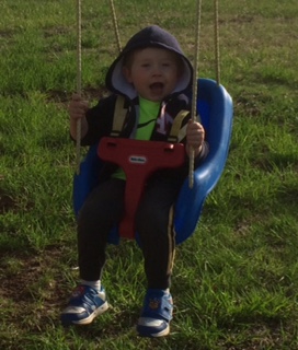 Young boy swinging in a Little Tikes swing