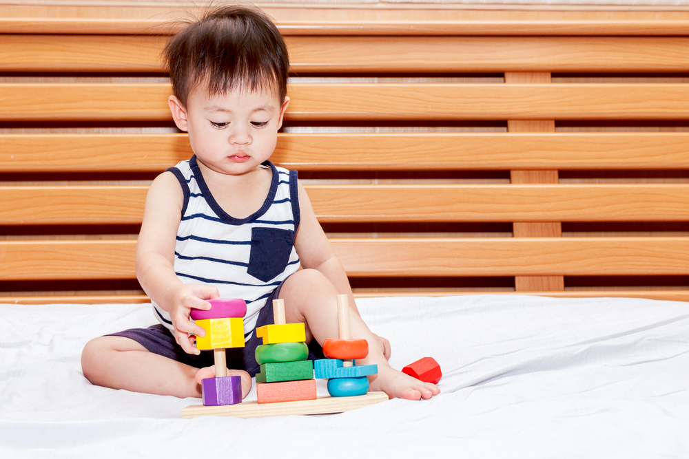 Asian toddler boy stacking colorful blocks