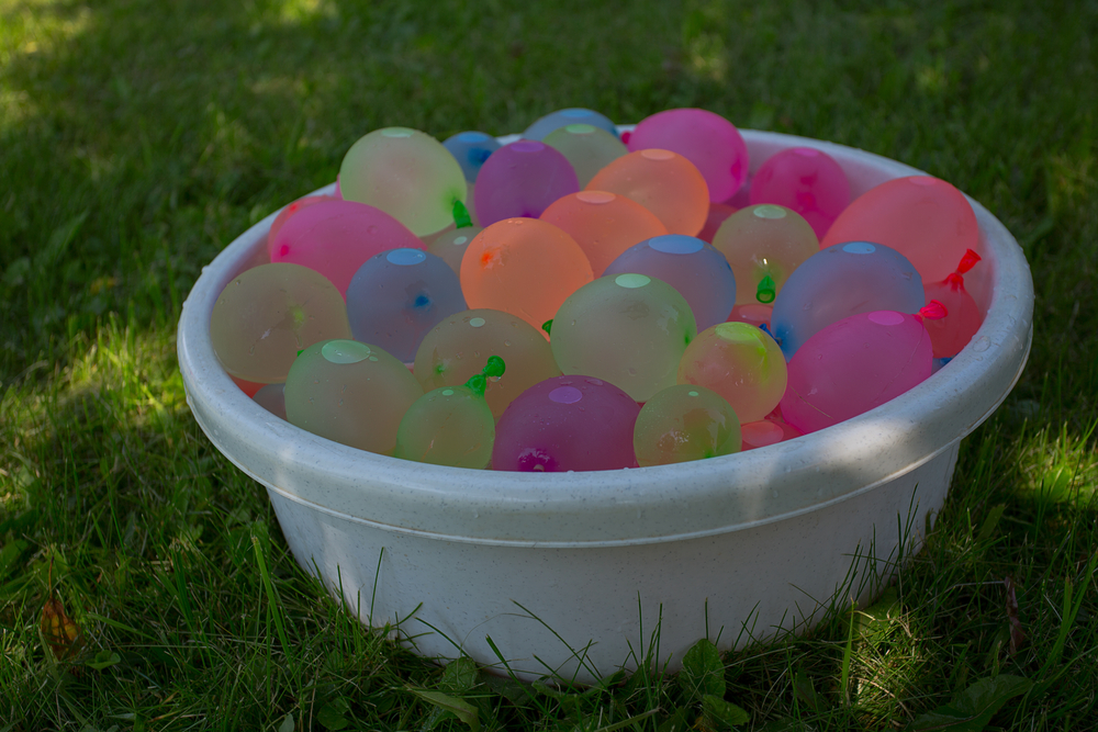 White plastic basket filled with colorful water balloons