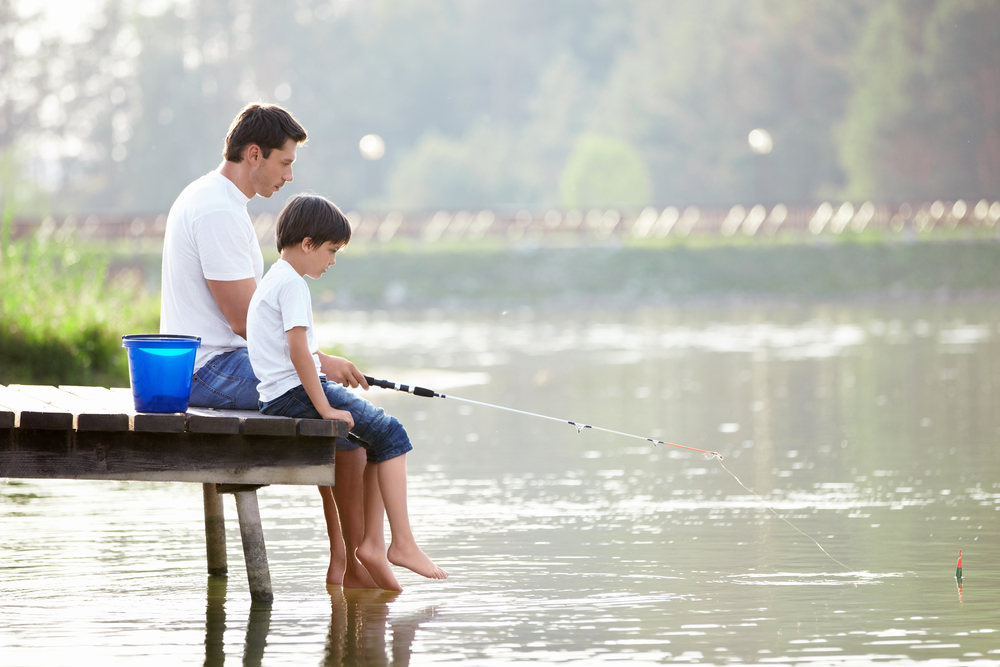 Father and son sitting on dock fishing