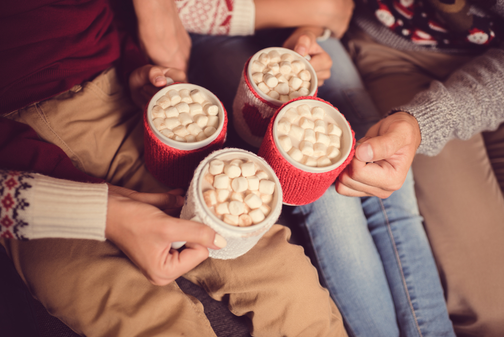 Family of four holding cups of hot cocoa with marshmallows