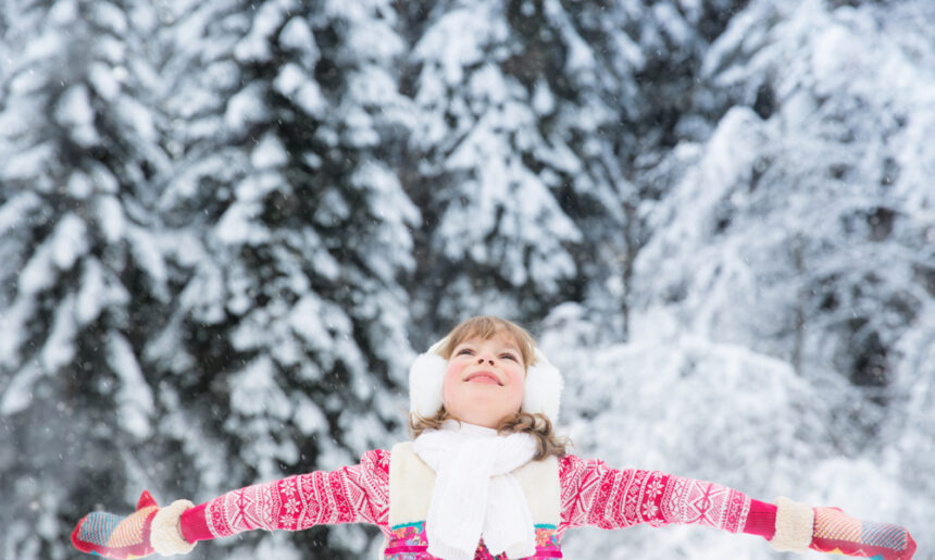 Girl standing in snow with arms outstretched