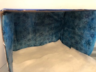 Inside view of box with blue tissue paper on sides and white felt on the bottom.