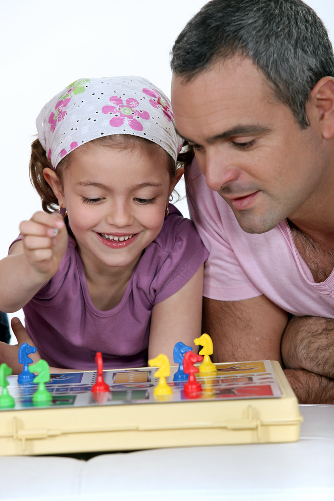 Little girl playing a board game with her father