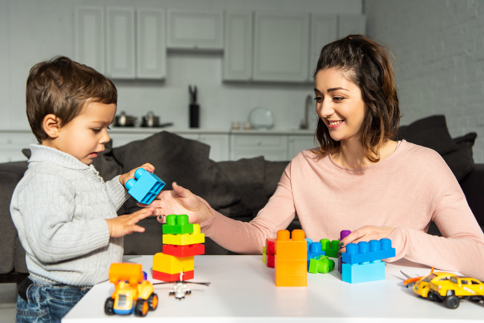 Mom and young son playing blocks together at table