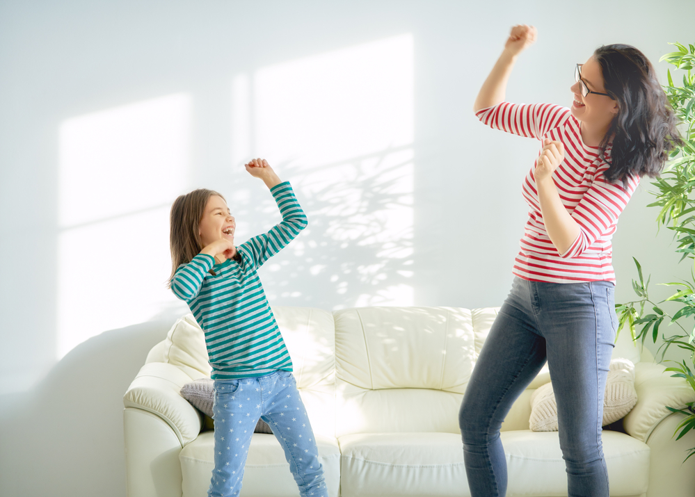 Mother and daughter dancing in front of a white sofa