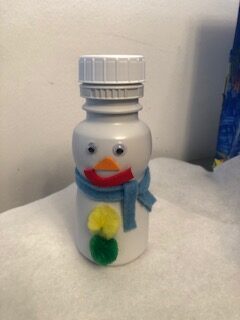 Snowman made out of white plastic bottle sitting on white felt